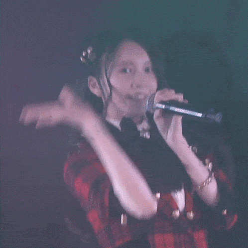 a woman is singing into a microphone with her hand in the air