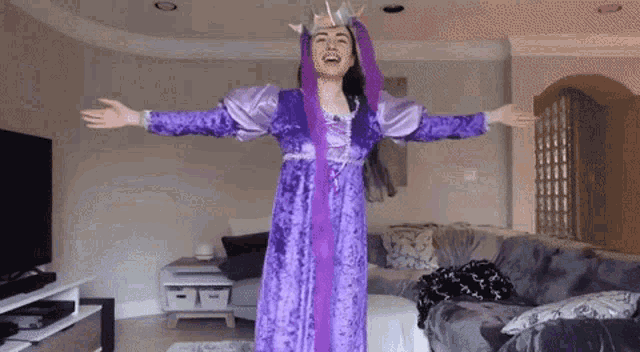 a woman in a purple dress is standing in a living room