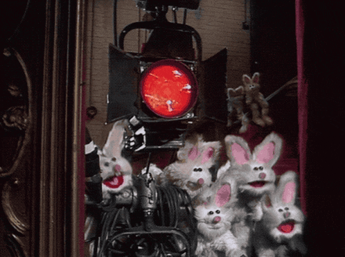 a bunch of stuffed rabbits with pink ears are behind a red light