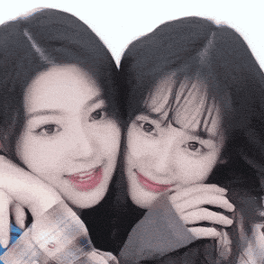 two girls are posing for a picture together and smiling for the camera .