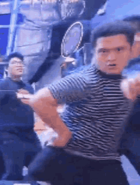 a man in a striped shirt is pointing at the camera while dancing .