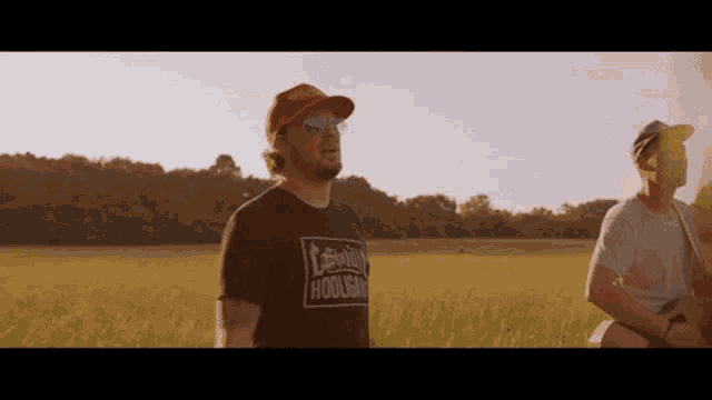 two men standing in a field one wearing a shirt that says lewis hooligan