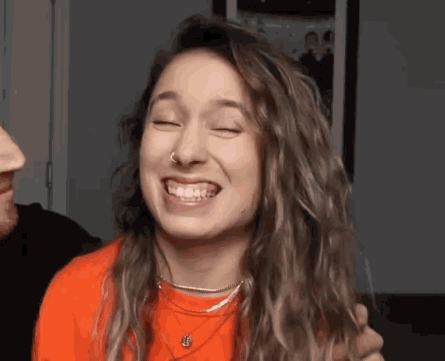 a woman with a nose ring is making a funny face with her eyes closed .