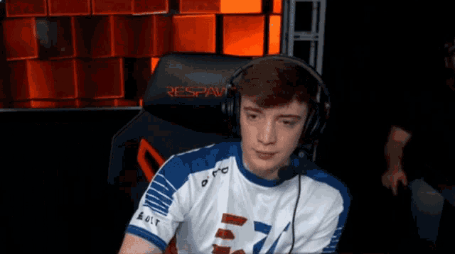 a man wearing headphones sits in a chair that says respawn on it