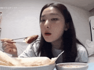 a woman is eating a piece of food with chopsticks .