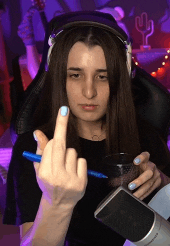 a woman wearing headphones is giving the middle finger while holding a pen