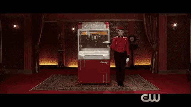 a man in a red uniform stands in front of a popcorn machine that says thunder