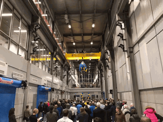 a crowd of people are gathered in a building with a sign that says ' flame ' on it