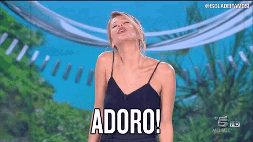 a woman in a black tank top is standing on a stage and saying adoro .