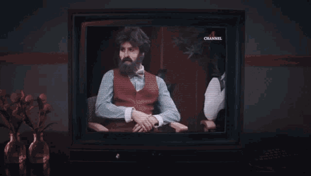 a television screen shows a man in a tuxedo and bow tie on channel 2