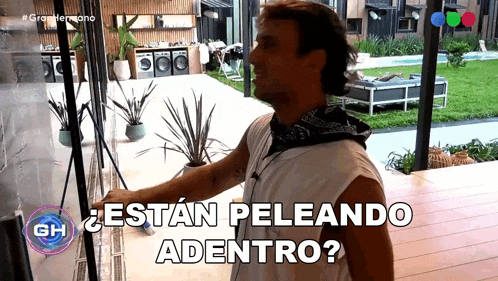 a man in a white tank top is standing in front of a glass door with the words " estan peleando adentro " above him