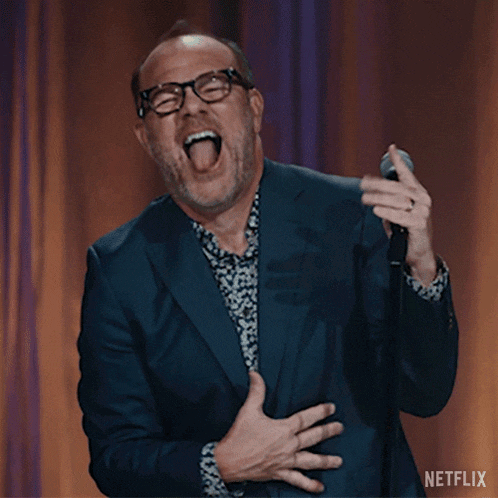 a man in a suit and glasses is singing into a microphone with a netflix logo in the corner