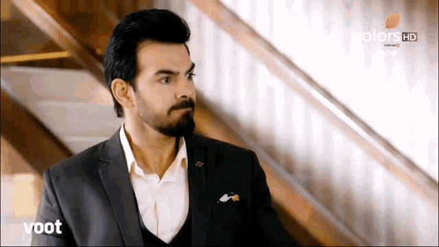 a man in a suit is standing in front of a wooden staircase with the words voot on the bottom