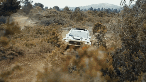 a white car is driving through a dirt field