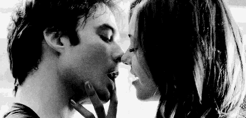 a man and a woman are kissing in a black and white photo . the woman is touching the man 's face .