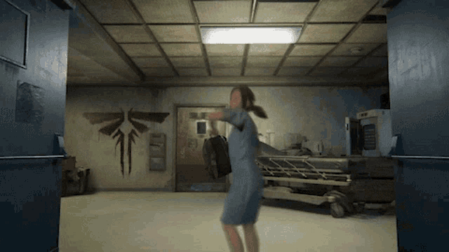 a woman in a blue dress stands in a hospital room