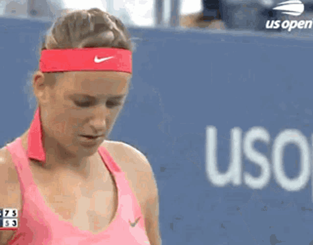 a woman wearing a red nike headband stands in front of a us open banner