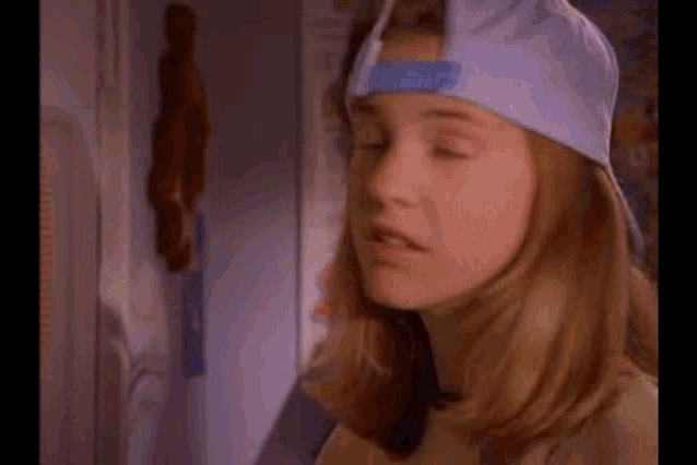 a young girl wearing a baseball cap with a blue tape on it .