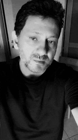a man with a beard wearing a black shirt is taking a selfie