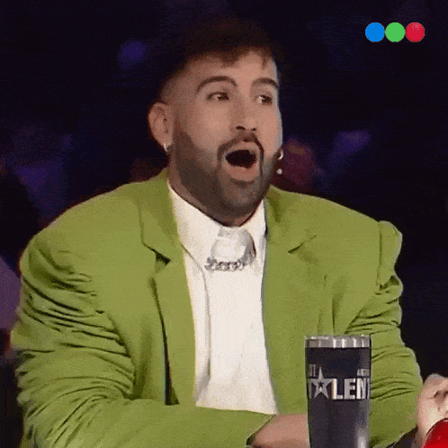 a man in a green jacket is sitting in front of a cup that says talent