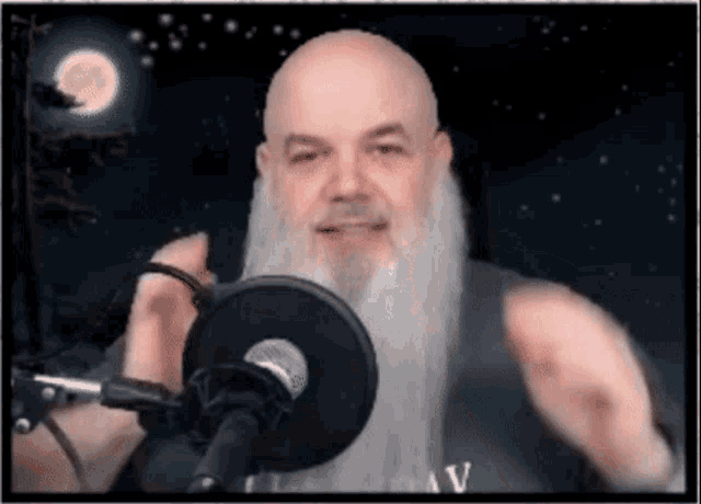 a man with a beard is speaking into a microphone with a full moon in the background