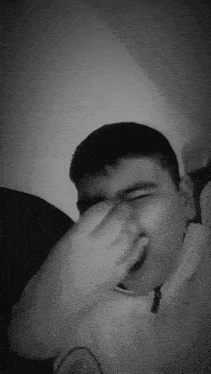 a black and white photo of a boy covering his face