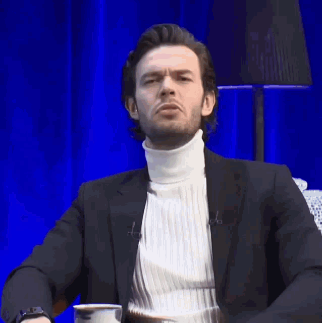 a man wearing a black jacket and a white turtleneck