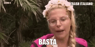 a woman wearing glasses and a flower crown is standing in the jungle and says basta .