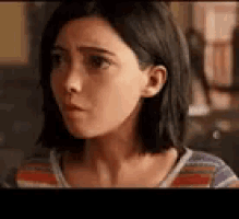 a woman with short hair is wearing a striped shirt and looking at the camera .
