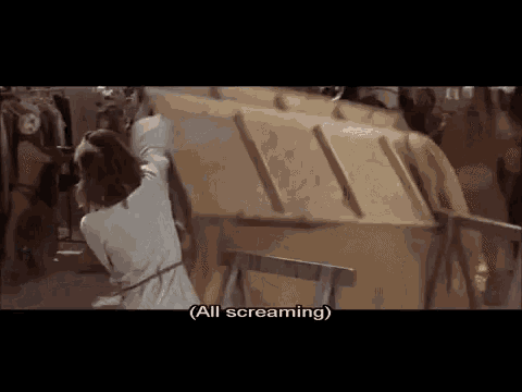 a woman in a white dress is holding a large piece of cardboard and says all screaming .