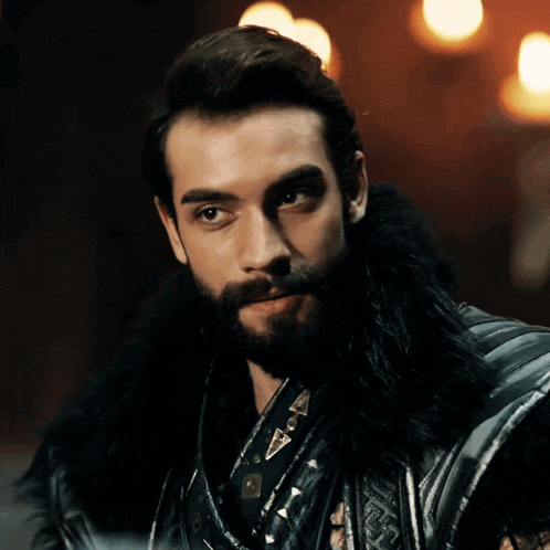a man with a beard is wearing a black fur collar