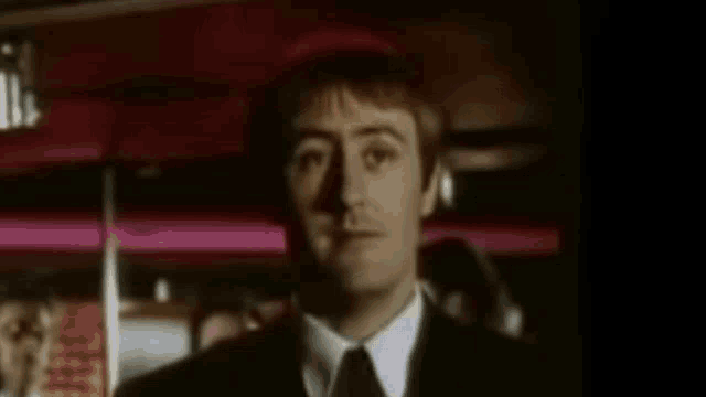 a man in a suit and tie looks at the camera in a dark room