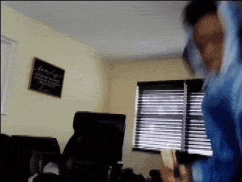 a person in a blue shirt is standing in front of a window in a room