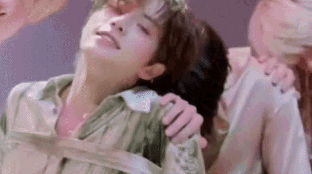 a man and a woman are standing next to each other . the woman is holding the man 's neck .