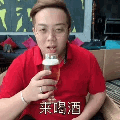a man in a red shirt is drinking from a wine glass