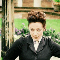 a woman wearing a black jacket and a white shirt is standing in front of flowers