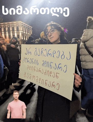 a woman holding a sign that says ' jm oakrpdj ' in blue letters
