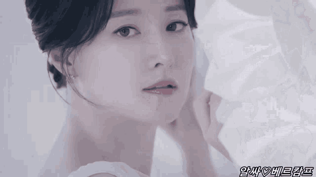 a close up of a woman 's face with a white dress on .