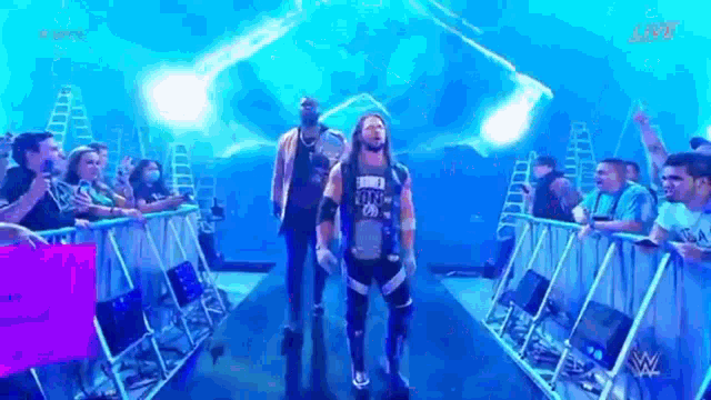 a wrestler is walking through a tunnel in front of a crowd of people .