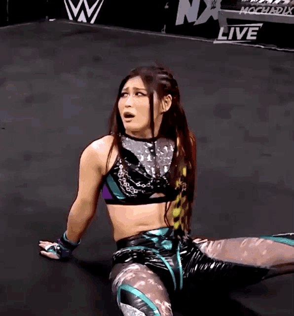 a female wrestler is kneeling down in front of a sign that says nx live