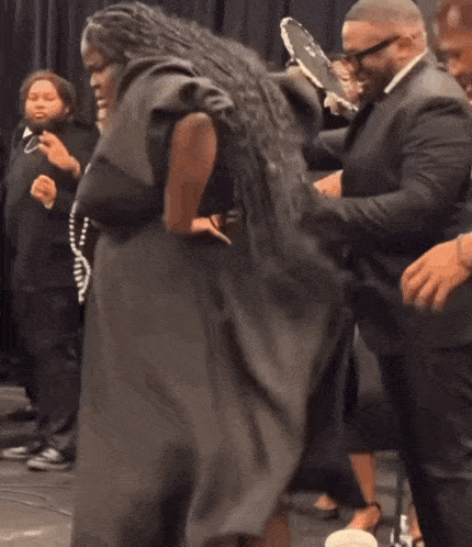 a woman in a black dress is dancing with a group of people