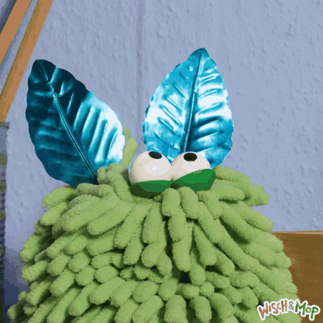 a green mop with blue leaves on it and the words wish mop on the bottom right