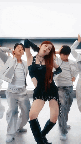 a woman in a black dress is dancing with a group of men in white clothes .