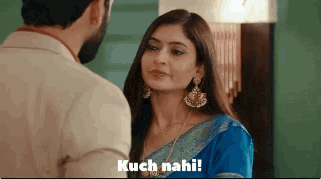 a man and a woman are looking at each other and the woman is wearing a blue saree