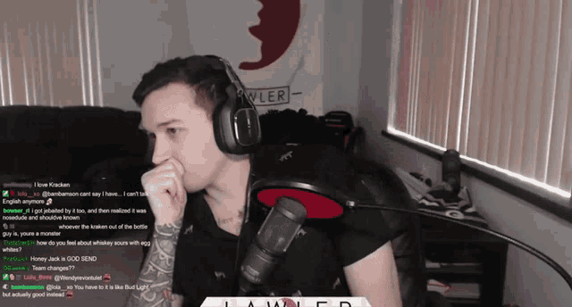 a man wearing headphones is sitting in front of a microphone and a sign that says kyler on it
