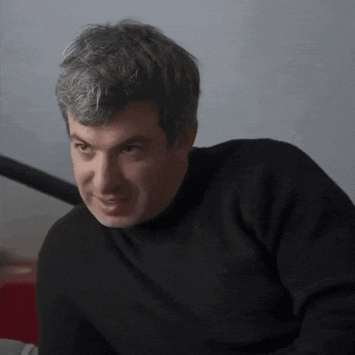 a man wearing a black sweater looks at the camera