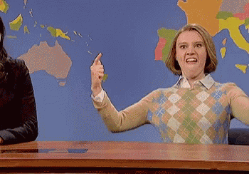 a woman is sitting at a desk in front of a map of the world and pointing at something .