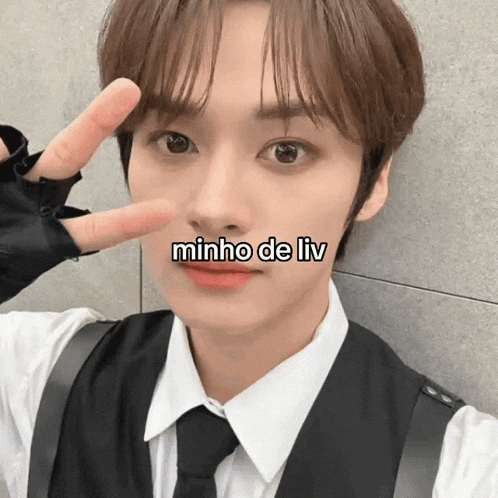 a young man in a suit and tie is making a peace sign with his finger .