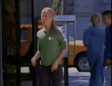 a woman in a green shirt is standing in front of a pay phone booth