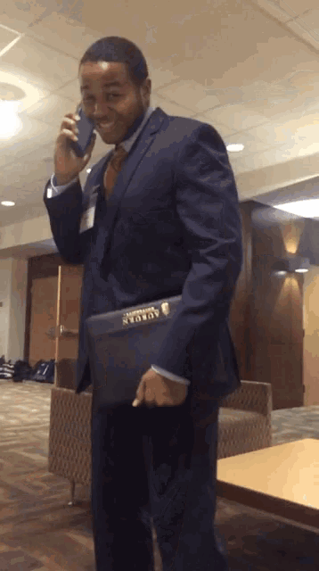 a man in a suit talking on a cell phone while holding a briefcase that says ' amanda '